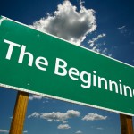 "The Beginning" Road Sign with dramatic blue sky and clouds.